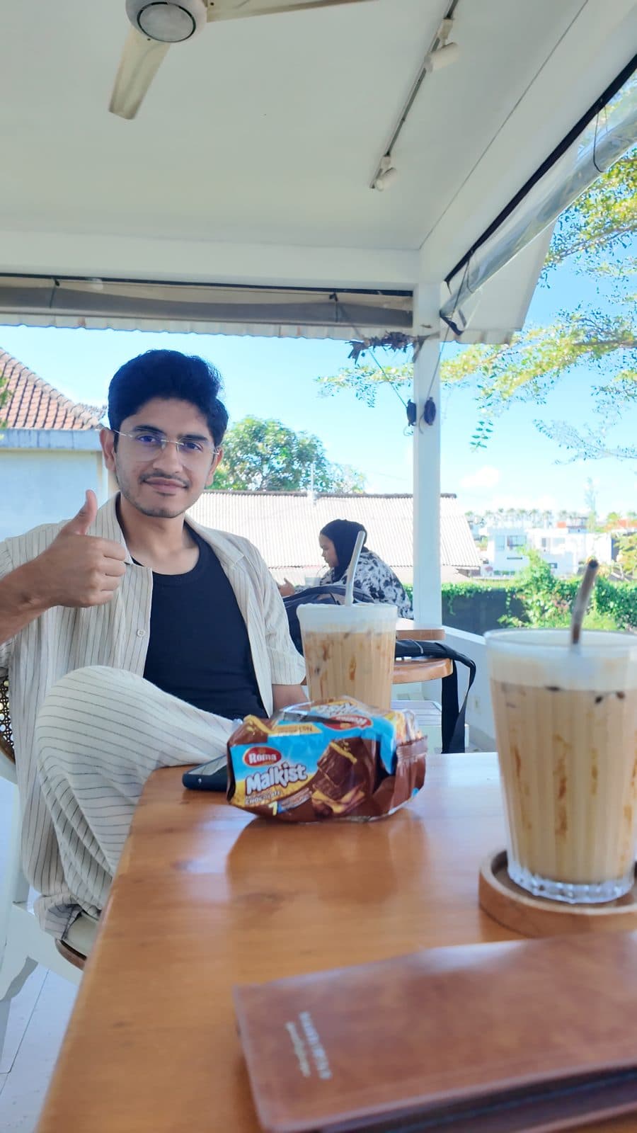 Thumbs up over an iced latte at a Bali cafe