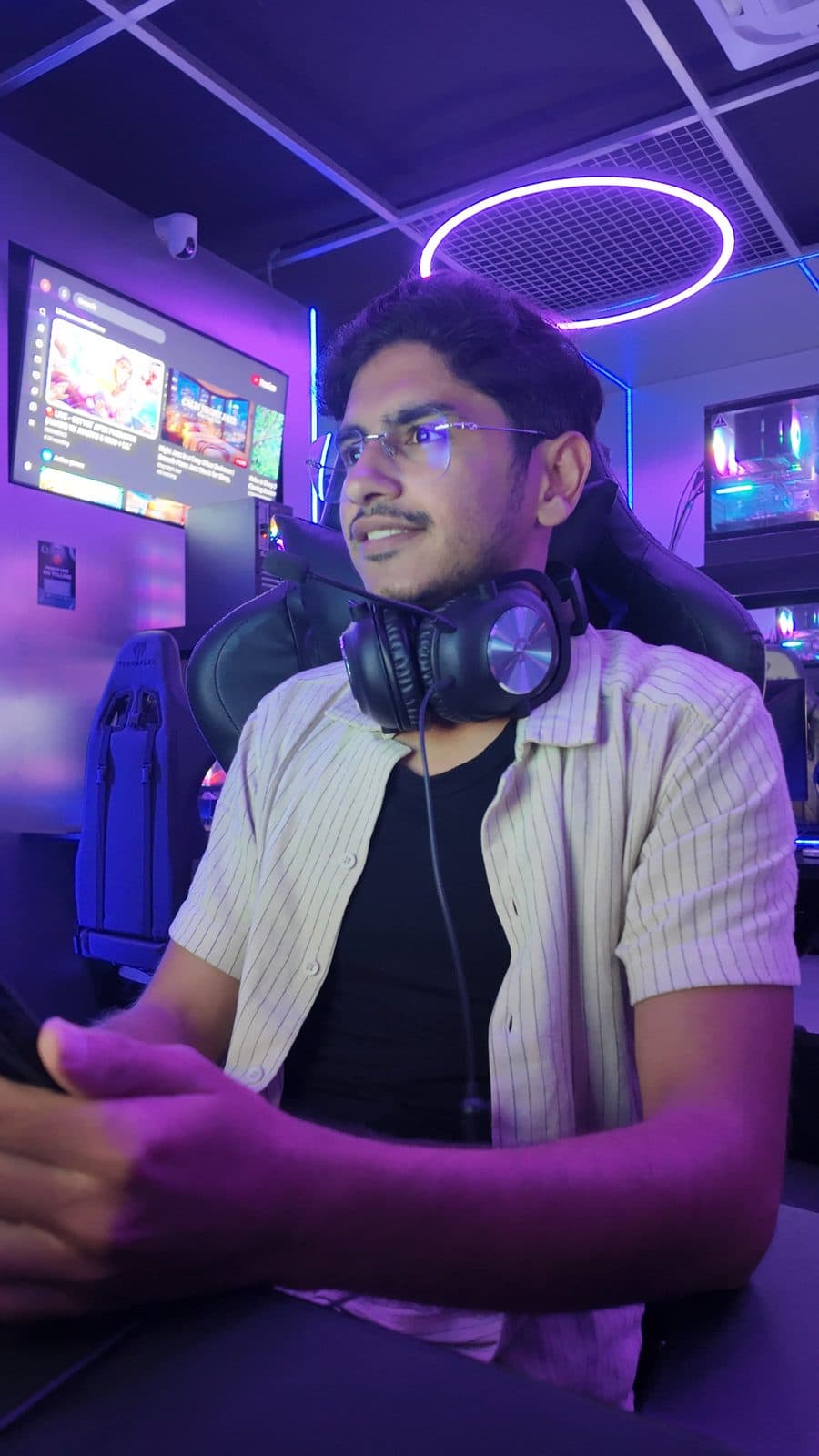 Candid in headphones at a neon-lit gaming cafe