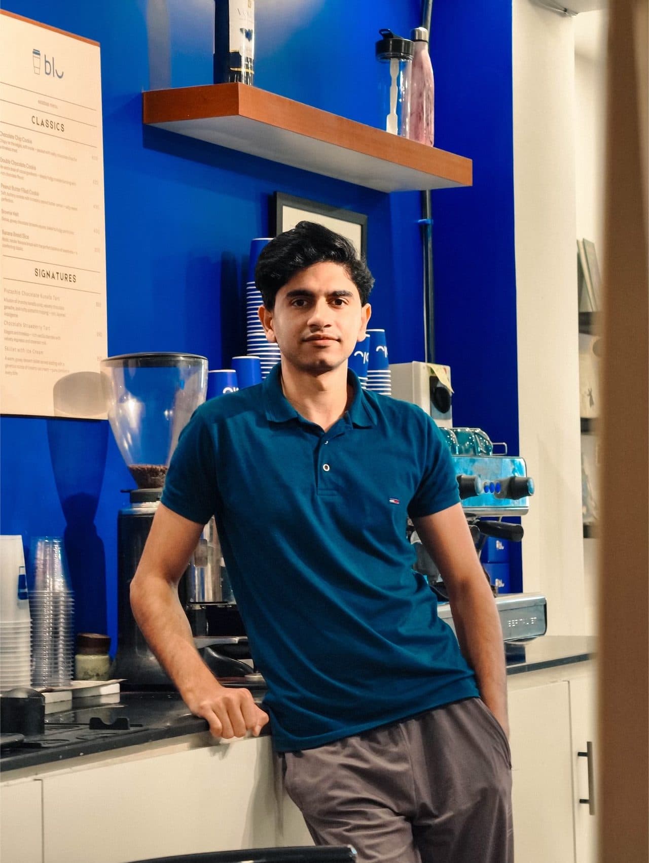 Behind a cafe counter by the espresso machine, facing camera