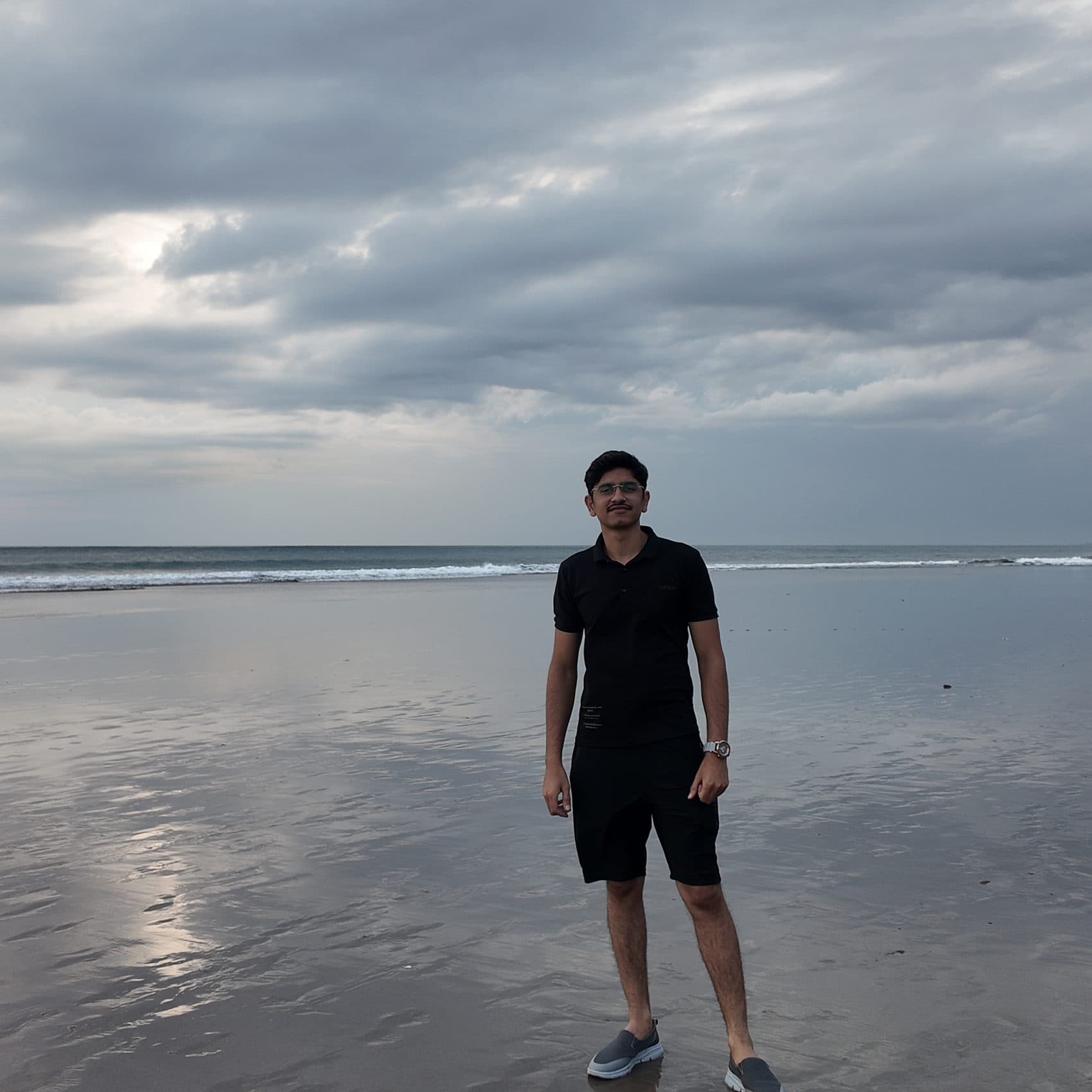 Standing on a beach under a moody sky, smiling