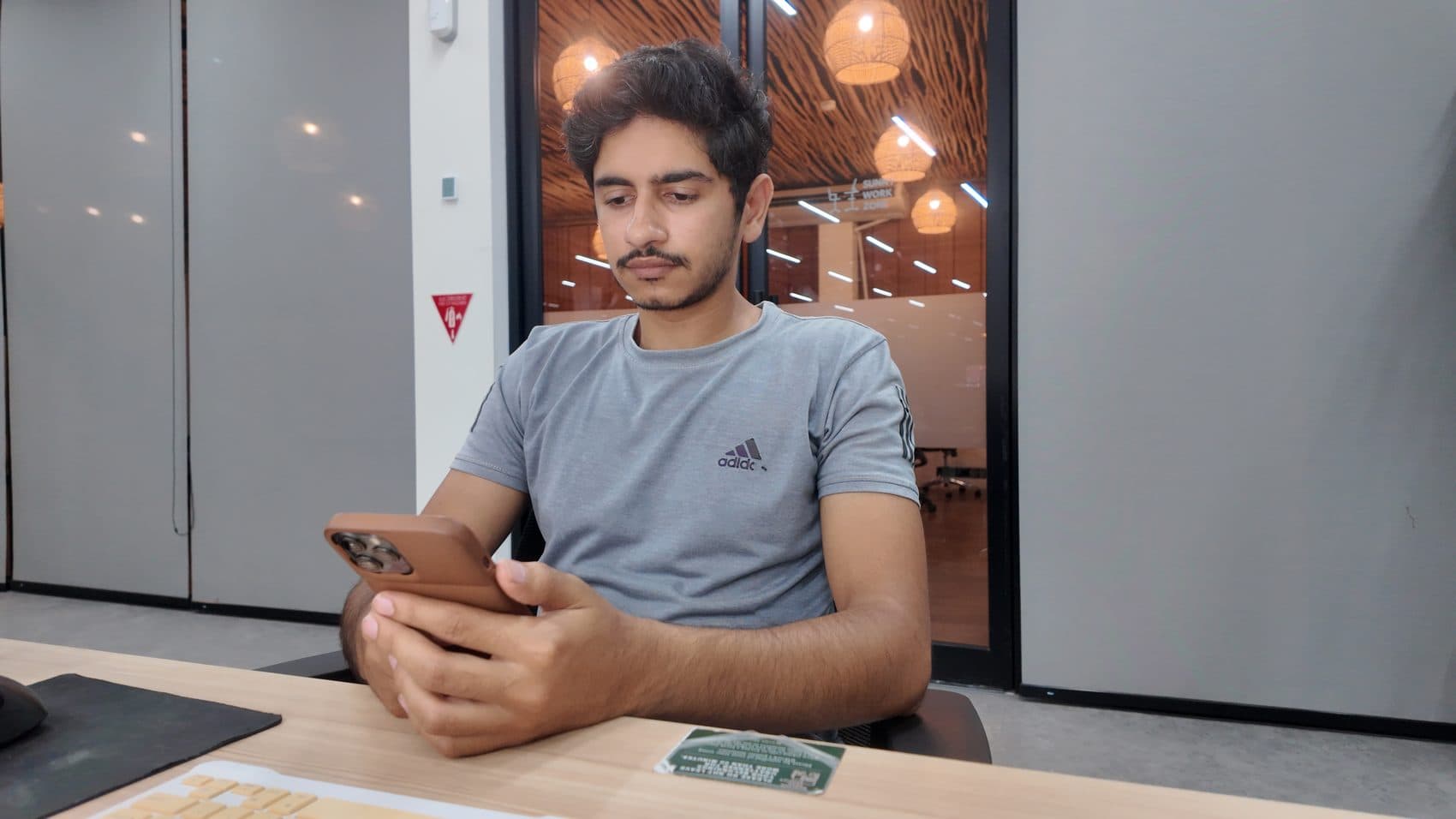 Waseem focused at a coworking desk, phone in hand